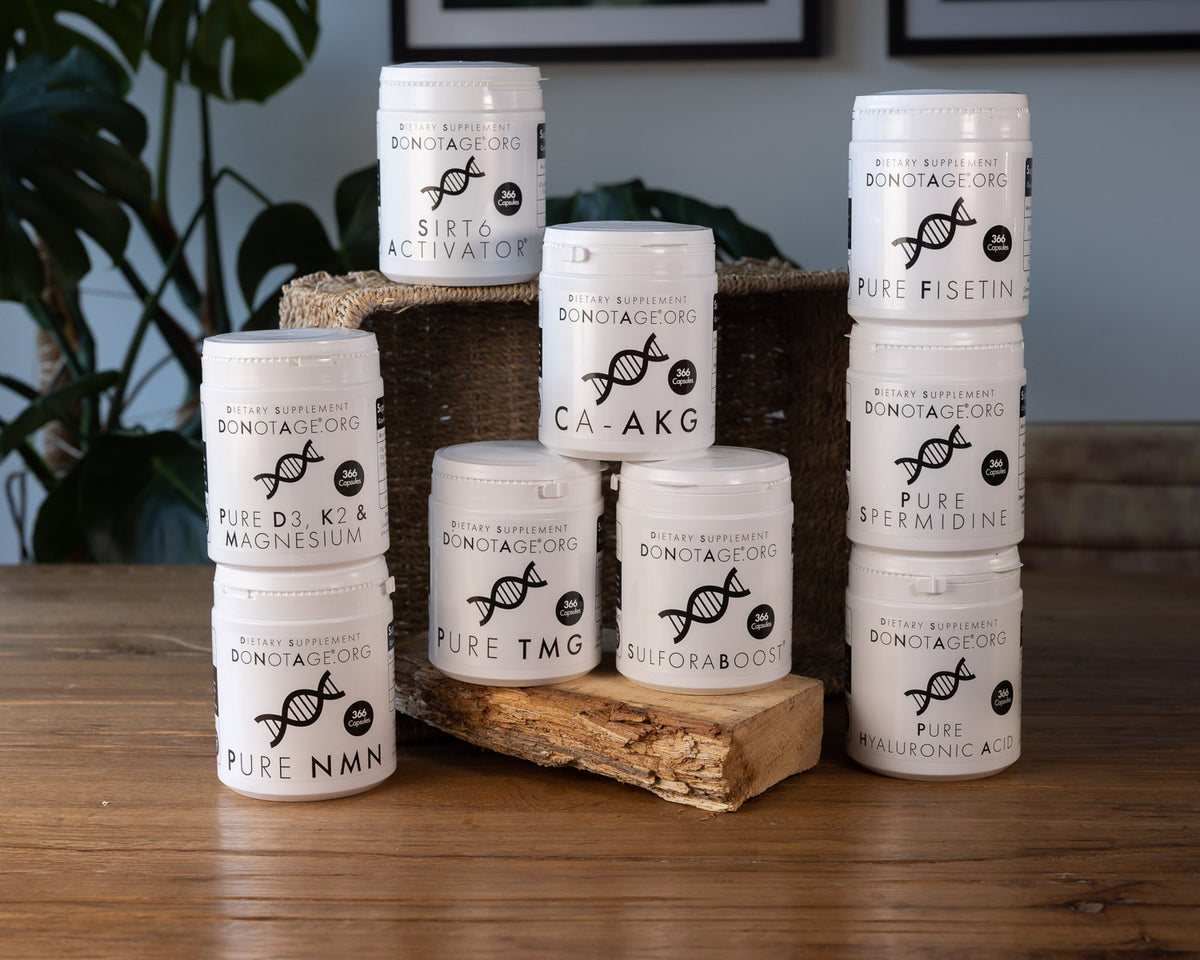 A group of white supplement jars with black labels arranged on a wooden surface and a rustic crate. The labels show the brand DONATOGEORG and product names including SIRT6 ACTIVATOR, CA-AKG, PURE NMN, PURE NMN, PURE TMG, and PURE SPERMIDINE.
